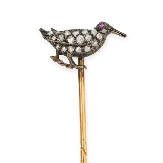 AN ANTIQUE DIAMOND AND RUBY BIRD STICK / TIE PIN designed as a bird set with rose cut diamonds,