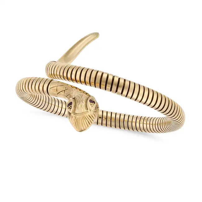 A VINTAGE RUBY SNAKE BANGLE in 9ct yellow gold, designed as a coiled snake, the eyes set with