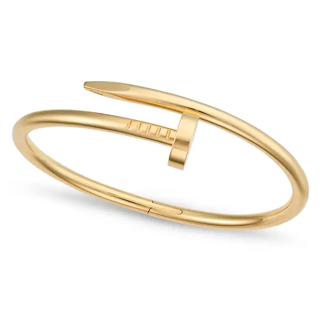 CARTIER, A CLASSIC MODEL JUSTE UN CLOU BANGLE in 18ct yellow gold, designed as bent nail, signed