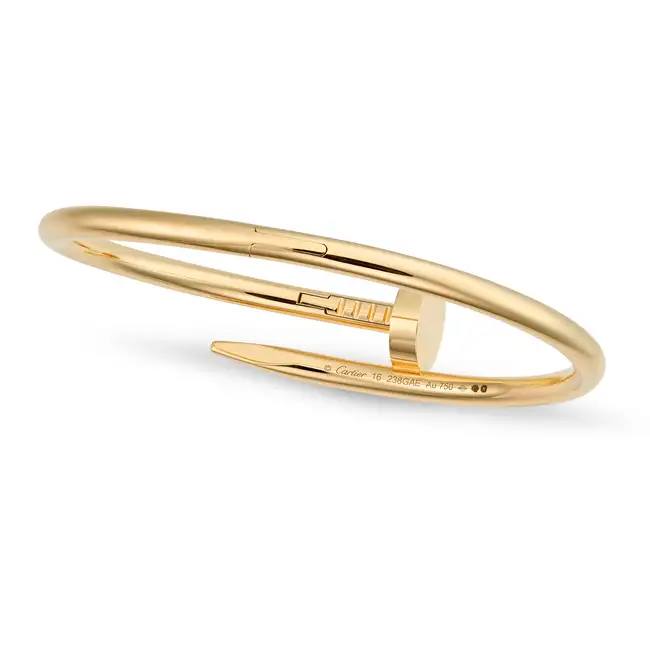 CARTIER, A CLASSIC MODEL JUSTE UN CLOU BANGLE in 18ct yellow gold, designed as bent nail, signed