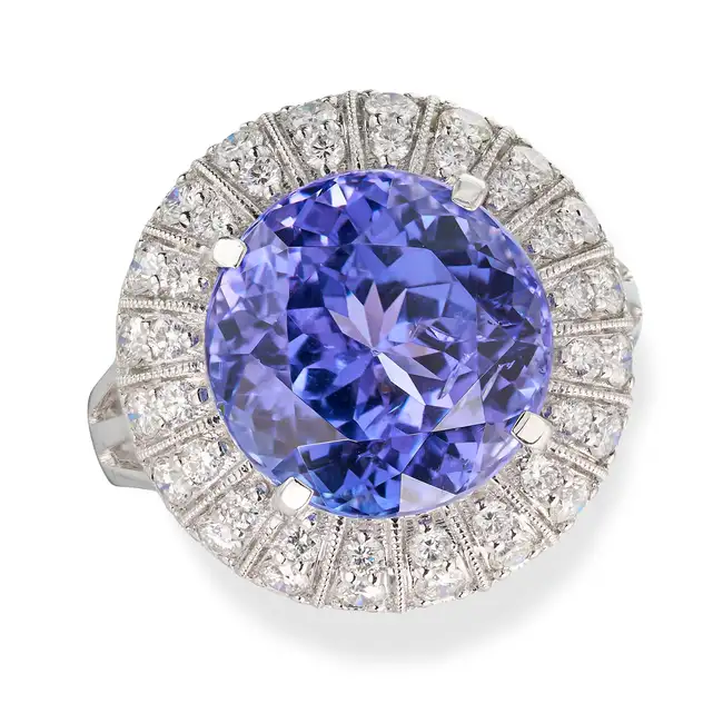 A TANZANITE AND DIAMOND DRESS RING set with a round cut tanzanite of 9.44 carats, the stylised