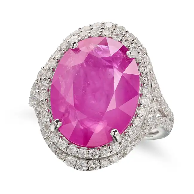 A RUBY AND DIAMOND DRESS RING set with an oval cut ruby of 12.06 carats in a double border of