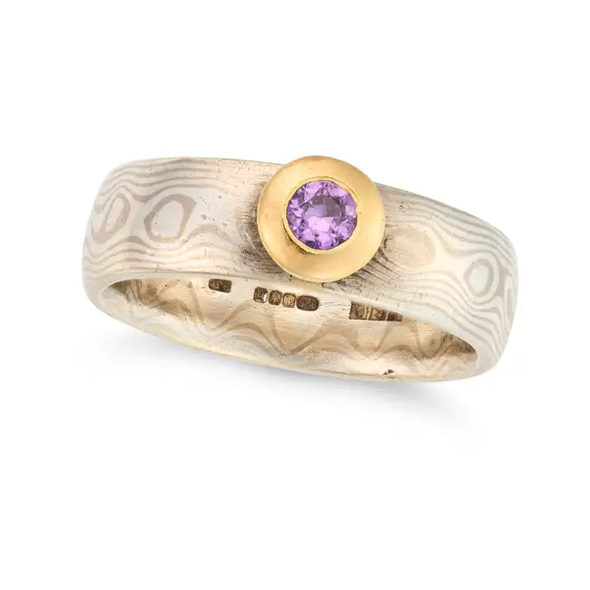 NO RESERVE - A SCOTTISH AMETHYST RING in silver, the stylised band set with a round cut amethyst,