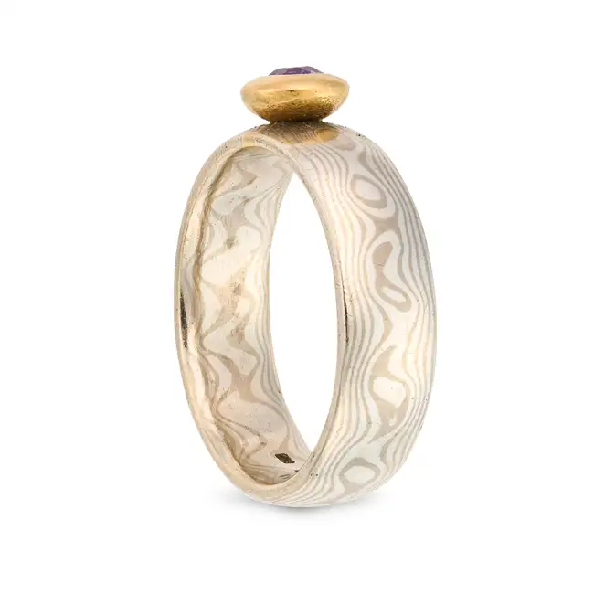NO RESERVE - A SCOTTISH AMETHYST RING in silver, the stylised band set with a round cut amethyst,
