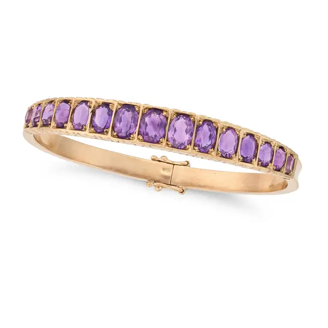 NO RESERVE - A VINTAGE AMETHYST BANGLE in 9ct yellow gold, the hinged bangle set with a graduating