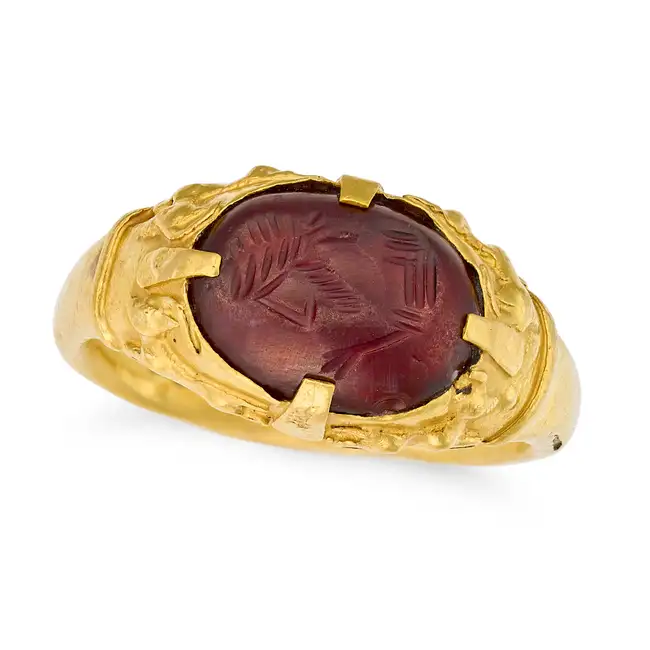 AN ANTIQUE GARNET INTAGLIO RING in yellow gold, set with a cabochon garnet carved to depict the