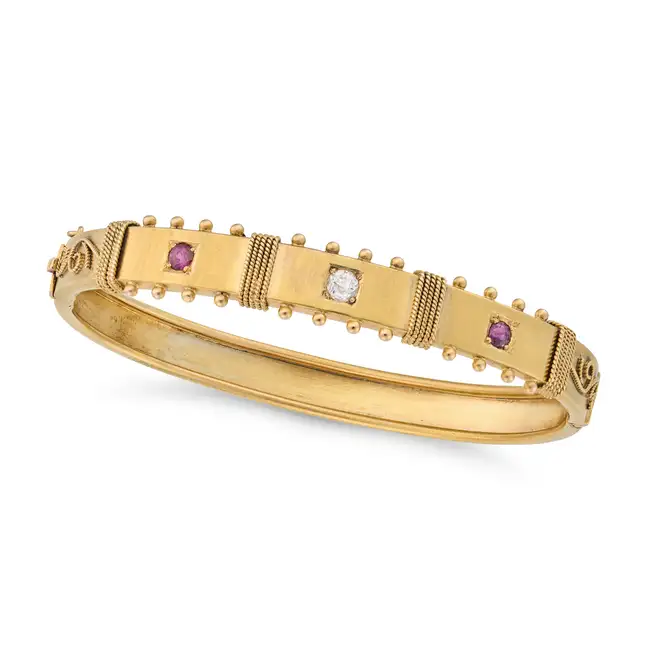 AN ANTIQUE RUBY AND DIAMOND BANGLE in yellow gold, the hinged body set to the front with an old