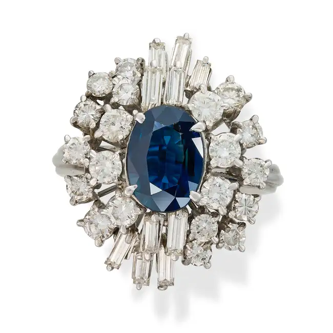 A SAPPHIRE AND DIAMOND DRESS RING set with an oval cut sapphire within a cluster of round