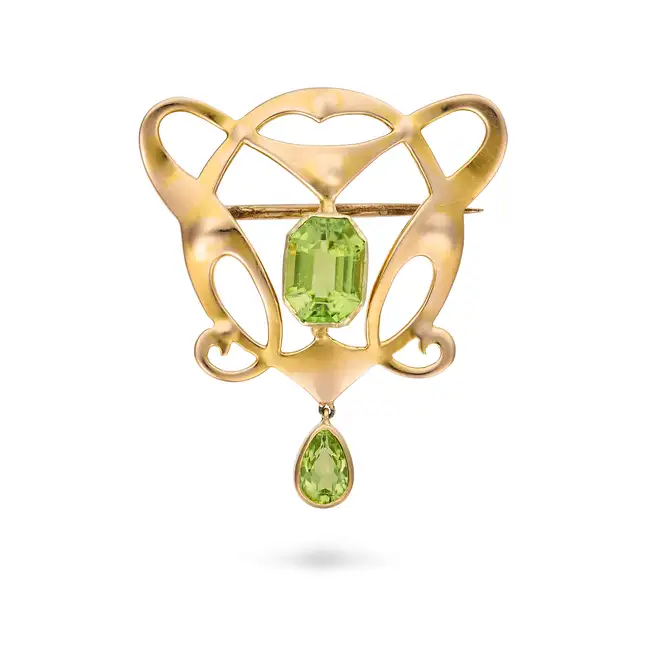 AN ANTIQUE ART NOUVEAU PERIDOT BROOCH in yellow gold, the scrolling brooch set with an octagonal