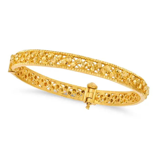 A GOLD BANGLE in high carat yellow gold, the hinged openwork bangle decorated with faceted gold