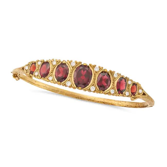 A GARNET AND DIAMOND BANGLE the hinged bangle set with graduating oval cut garnets, accented by