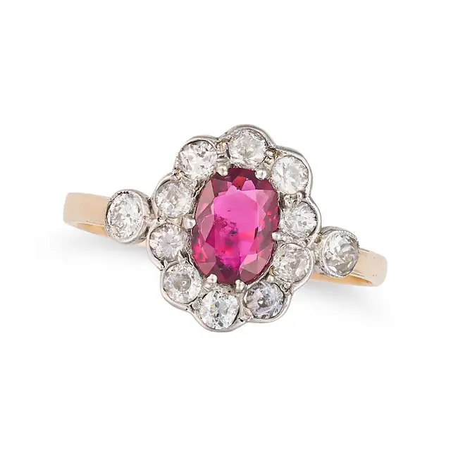 AN ANTIQUE RUBY AND DIAMOND CLUSTER RING in yellow gold, set with a cushion cut ruby of