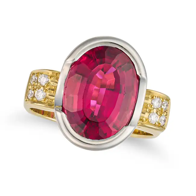 A RUBELLITE TOURMALINE AND DIAMOND DRESS RING set with an oval cut rubellite tourmaline of 5.17
