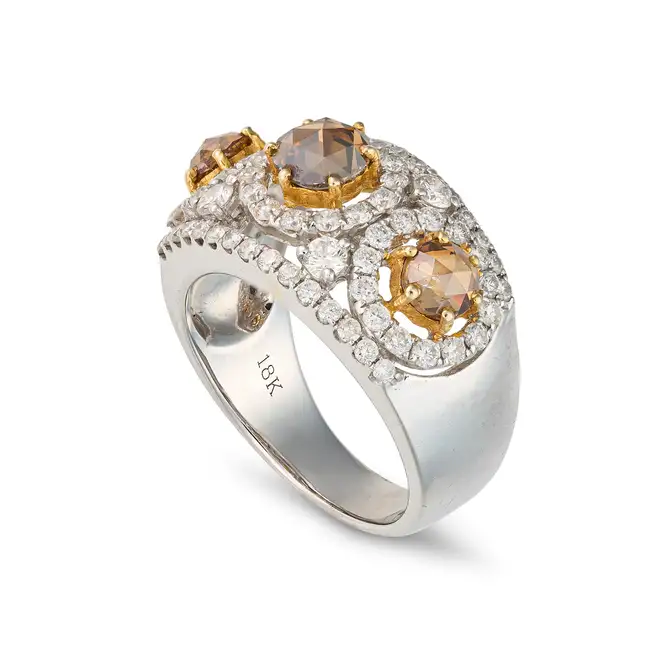 A FANCY COLOUR DIAMOND DRESS RING set with three rose cut diamonds totalling 1.36 carats, accented