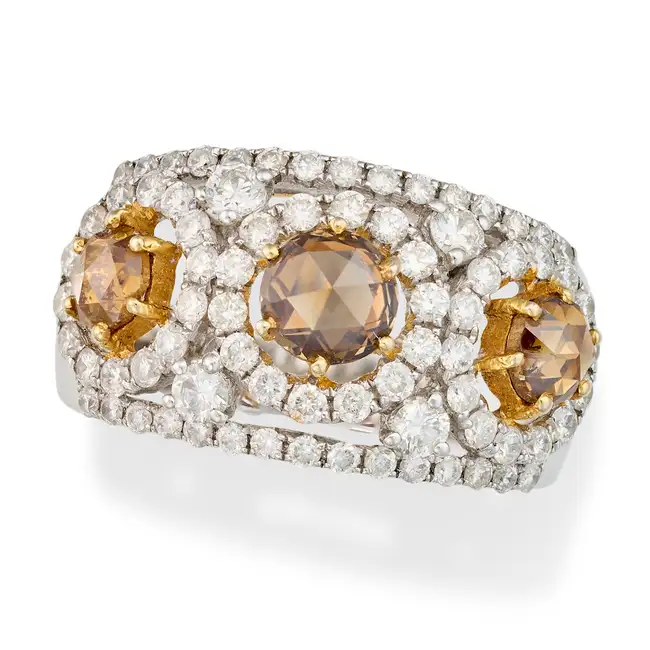 A FANCY COLOUR DIAMOND DRESS RING set with three rose cut diamonds totalling 1.36 carats, accented