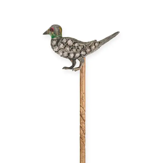 AN ANTIQUE DIAMOND AND GARNET BIRD STICK / TIE PIN designed as a bird set with rose cut diamonds,