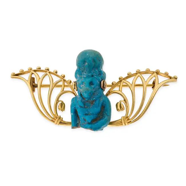 AN EGYPTIAN REVIVAL FAIENCE BROOCH depicting the Egyptian goddess Sekhment, accented by lotus