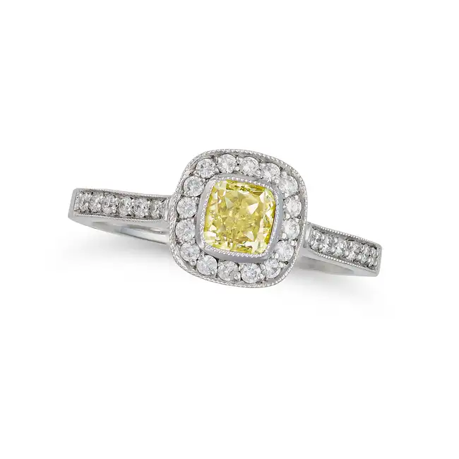 A FANCY YELLOW DIAMOND AND DIAMOND RING in platinum, set with a cushion cut yellow diamond of 0.60
