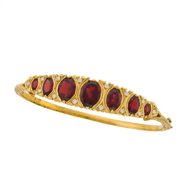 A GARNET AND DIAMOND BANGLE the hinged bangle set with a row of graduating oval cut garnets,