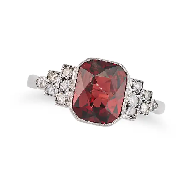 A GARNET AND DIAMOND RING set with an octagonal mixed garnet, the stepped shoulders set with