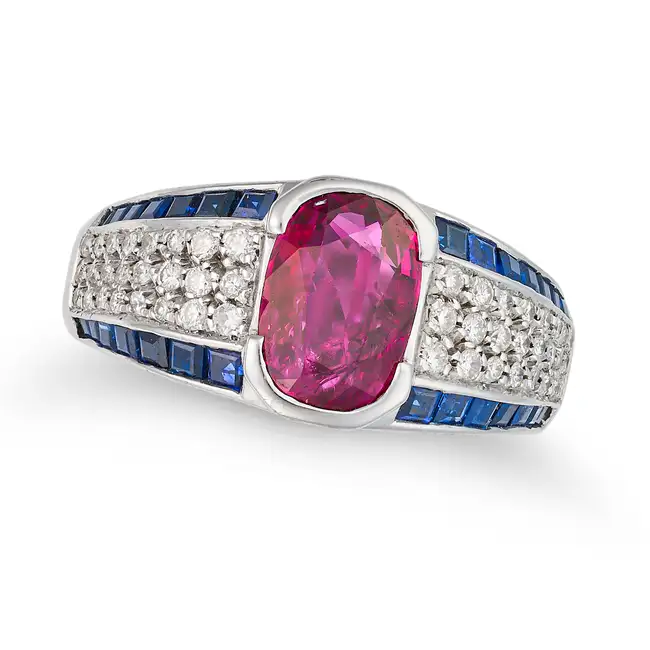 A RUBY, SAPPHIRE AND DIAMOND DRESS RING set with a cushion cut ruby of approximately 050 carats, the