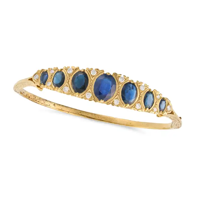 NO RESERVE - A SAPPHIRE AND DIAMOND BANGLE in yellow gold, the hinged bangle set with a row of