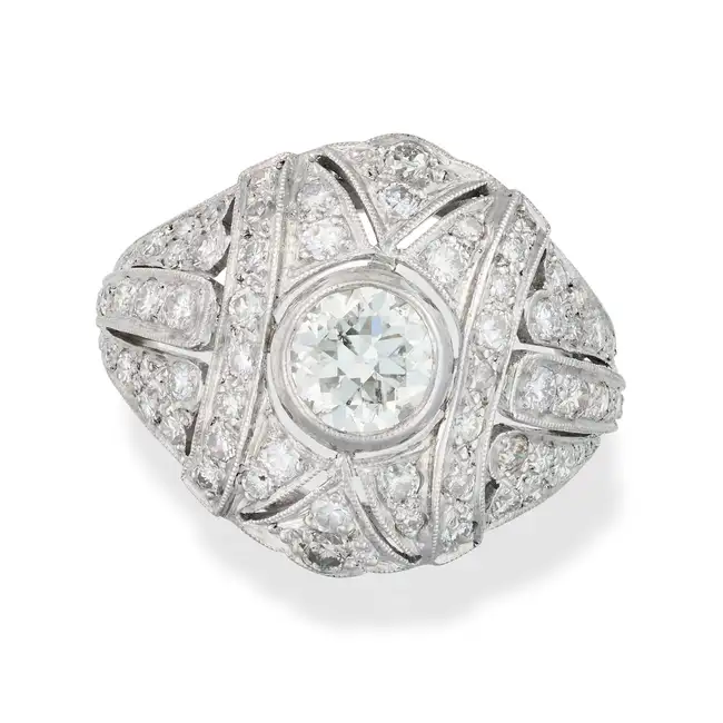 A DIAMOND DRESS RING in Art Deco design, the pierced bombe ring set with an old cut diamond of