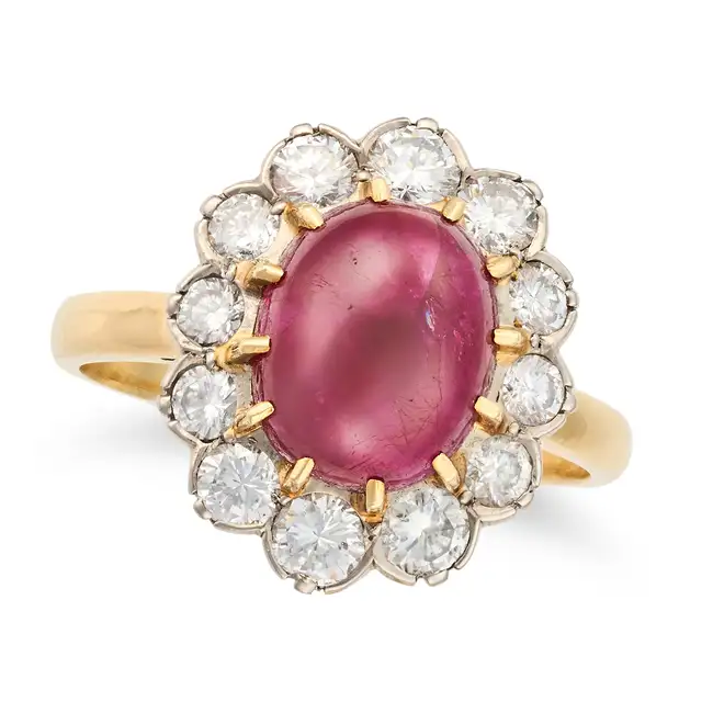 A FRENCH RUBY AND DIAMOND CLUSTER RING set with an oval cabochon ruby of approximately 5.25