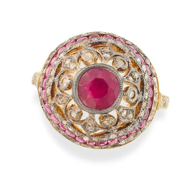 A RUBY AND DIAMOND DRESS RING in silver gilt, the domed ring set with a round cut ruby, accented