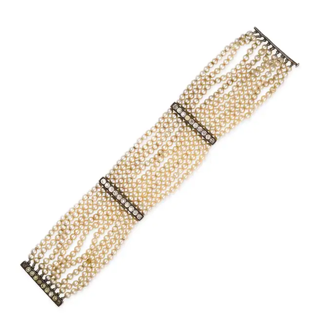 AN ANTIQUE FAUX PEARL AND PASTE BRACELET comprising nine rows of faux pearls, accented by spacers
