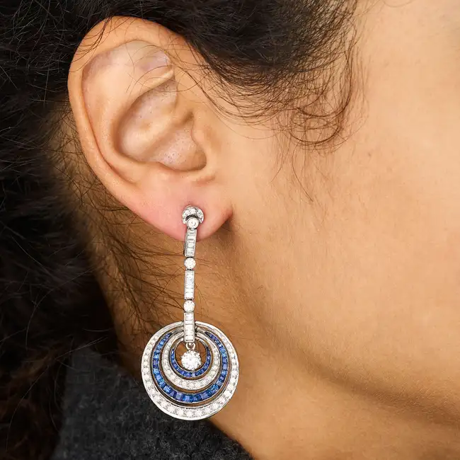 A PAIR OF DIAMOND AND SAPPHIRE DROP EARRINGS each suspending a round brilliant cut diamond within
