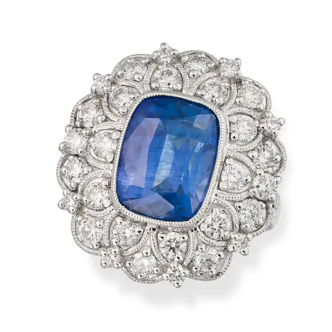 OSCAR FRIEDMAN, A SAPPHIRE AND DIAMOND CLUSTER RING set with a cushion cut sapphire of 8.39