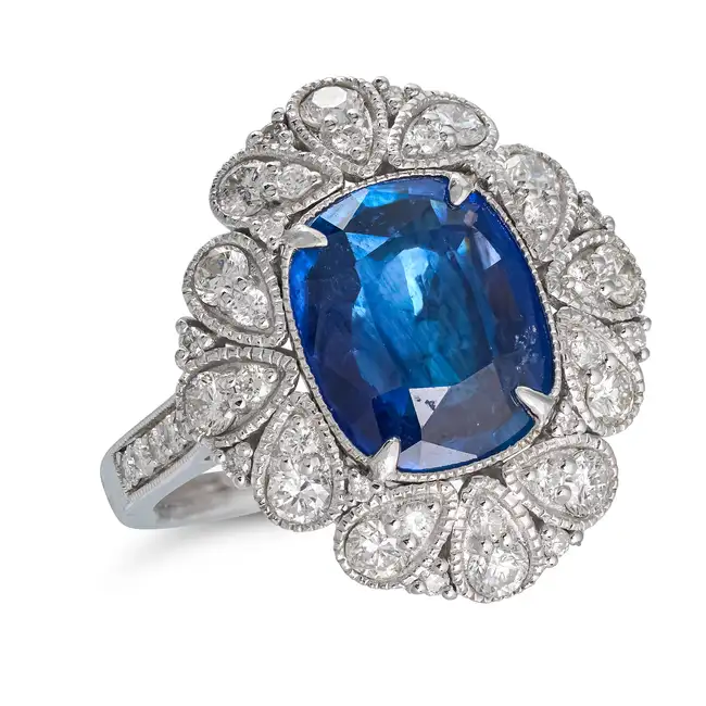 A CEYLON SAPPHIRE AND DIAMOND DRESS RING set with a cushion cut sapphire of 3.85 carats, accented by