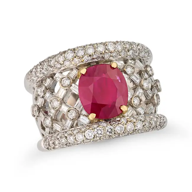 A RUBY AND DIAMOND DRESS RING in lattice design, set with a cushion cut ruby of approximately 2.17