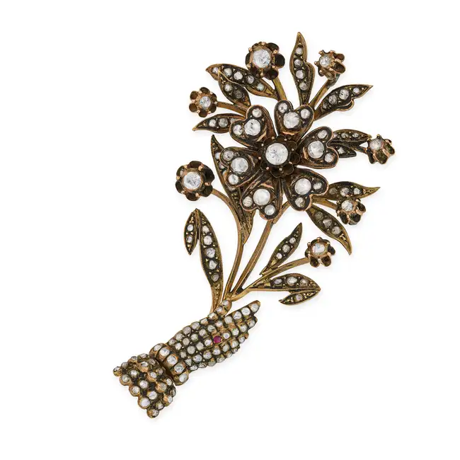 A DIAMOND FLORAL SPRAY BROOCH designed as an articulated hand holding a floral spray, set throughout