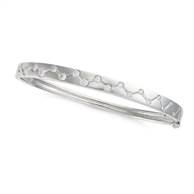 A DIAMOND BANGLE in 18ct white gold, the hinged bangle with a stylised design accented by round
