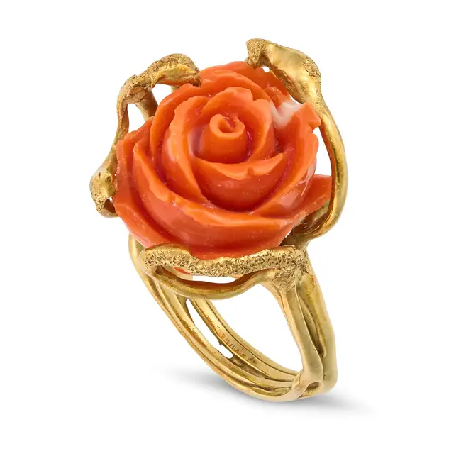 AN ITALIAN CORAL ROSE RING in yellow gold, set with a carved coral rose, the band in stylised