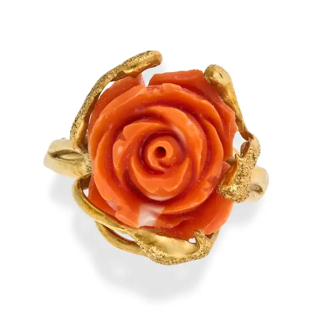 AN ITALIAN CORAL ROSE RING in yellow gold, set with a carved coral rose, the band in stylised