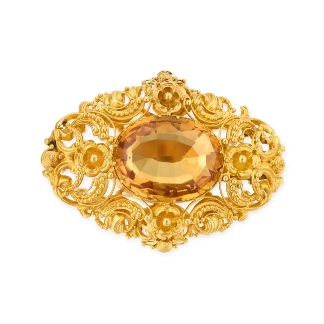AN ANTIQUE CITRINE BROOCH set with an oval cut citrine, within a foliate style frame accented by