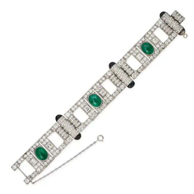 A FINE ART DECO EMERALD, DIAMOND AND ONYX STRAP BRACELET comprising a row of geometric motifs with