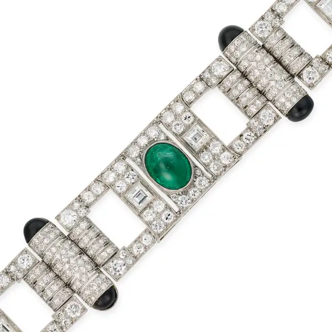 A FINE ART DECO EMERALD, DIAMOND AND ONYX STRAP BRACELET comprising a row of geometric motifs with