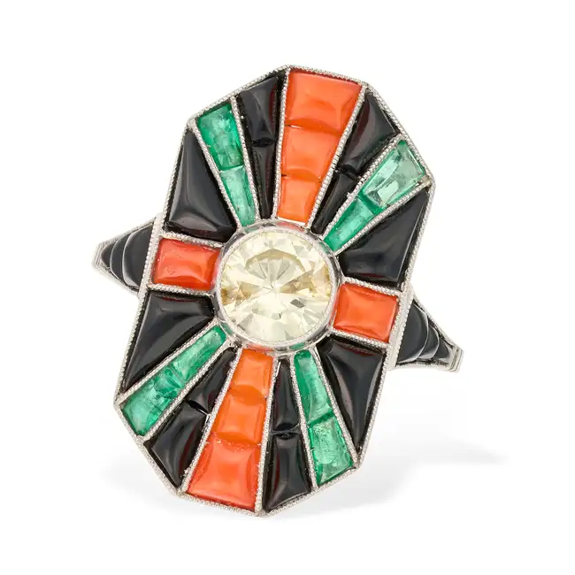 AN ART DECO DIAMOND, CORAL, ONYX AND EMERALD DRESS RING set with a round brilliant cut diamond of