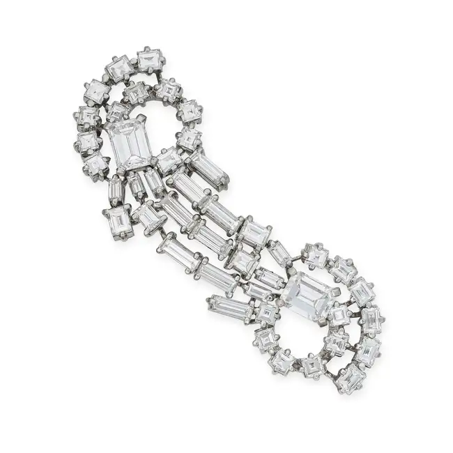 RAYMOND YARD, A MID CENTURY DIAMOND BROOCH in scrolling design, set with emerald, baguette and carre