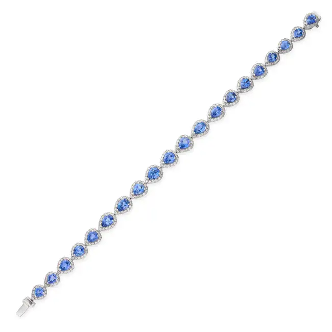A CEYLON SAPPHIRE AND DIAMOND BRACELET set with a row of pear cut sapphires in borders of round