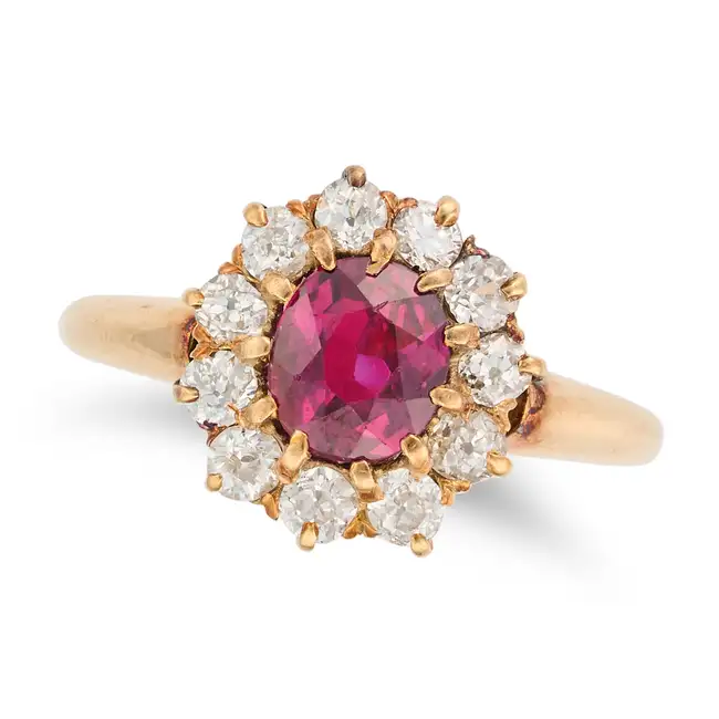 AN ANTIQUE RUBY AND DIAMOND CLUSTER RING in yellow gold, set with an oval cut ruby of