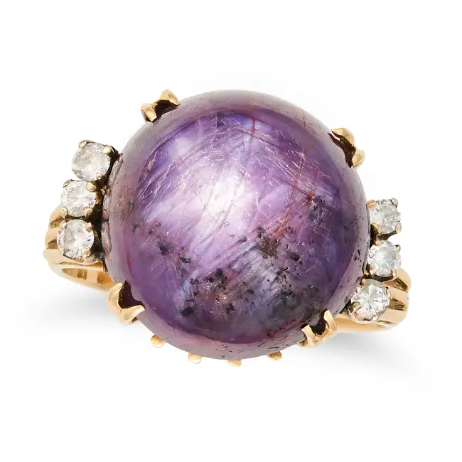 A STAR PURPLE SAPPHIRE AND DIAMOND RING set with a cabochon purple star sapphire of approximately