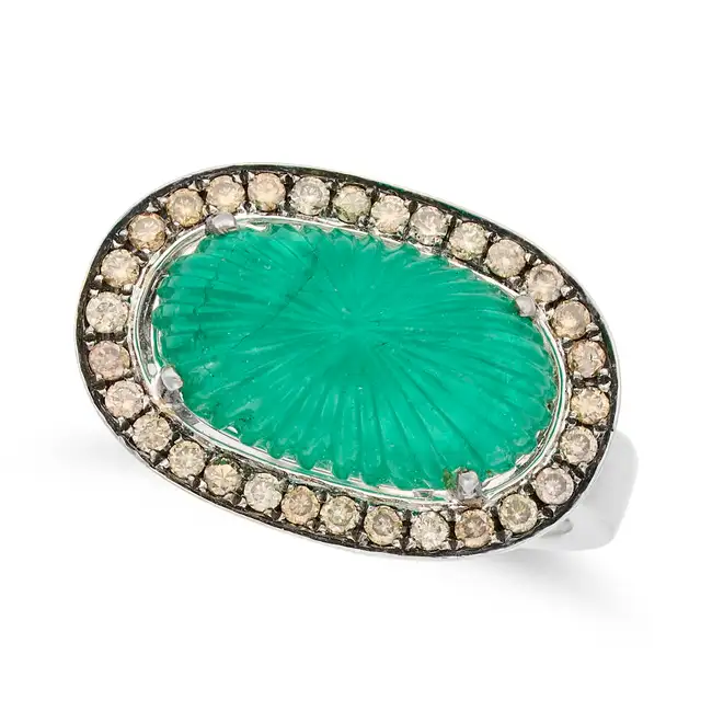 A CARVED EMERALD AND DIAMOND RING set with a carved cabochon emerald of 4.69 carats, within a border