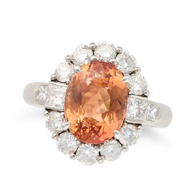 A FINE IMPERIAL TOPAZ AND DIAMOND CLUSTER RING set with an oval cut imperial topaz of 5.04 carats in