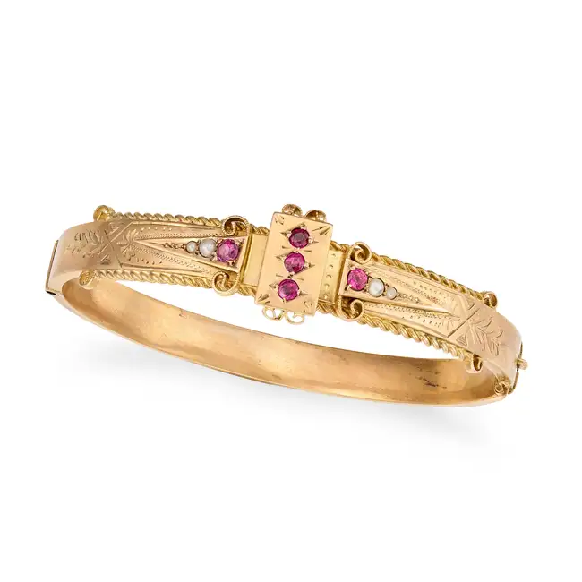 AN ANTIQUE VICTORIAN RUBY AND PEARL BANGLE in 9ct yellow gold, the hinged bangle set with round