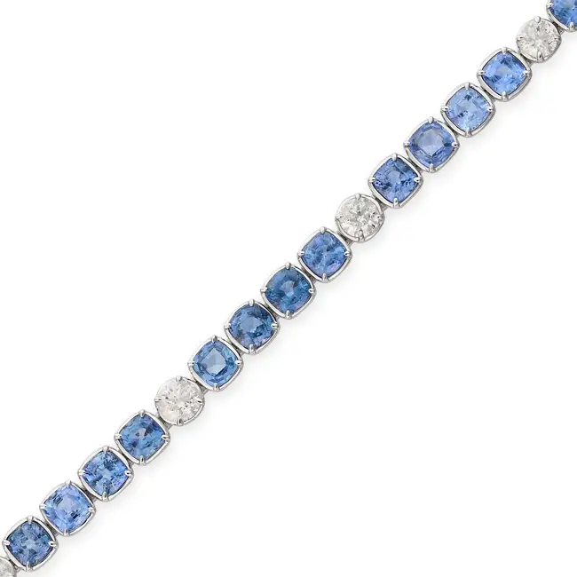 OSCAR FRIEDMAN, A SAPPHIRE AND DIAMOND LINE BRACELET set with a row of cushion cut sapphires,